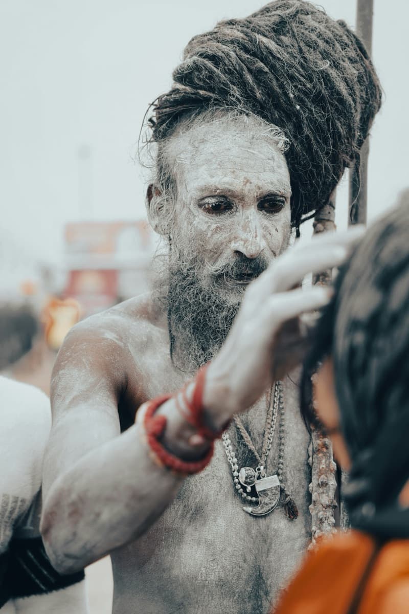 Ash-smeared Naga Sadhu blessing a devotee at the Kumbh